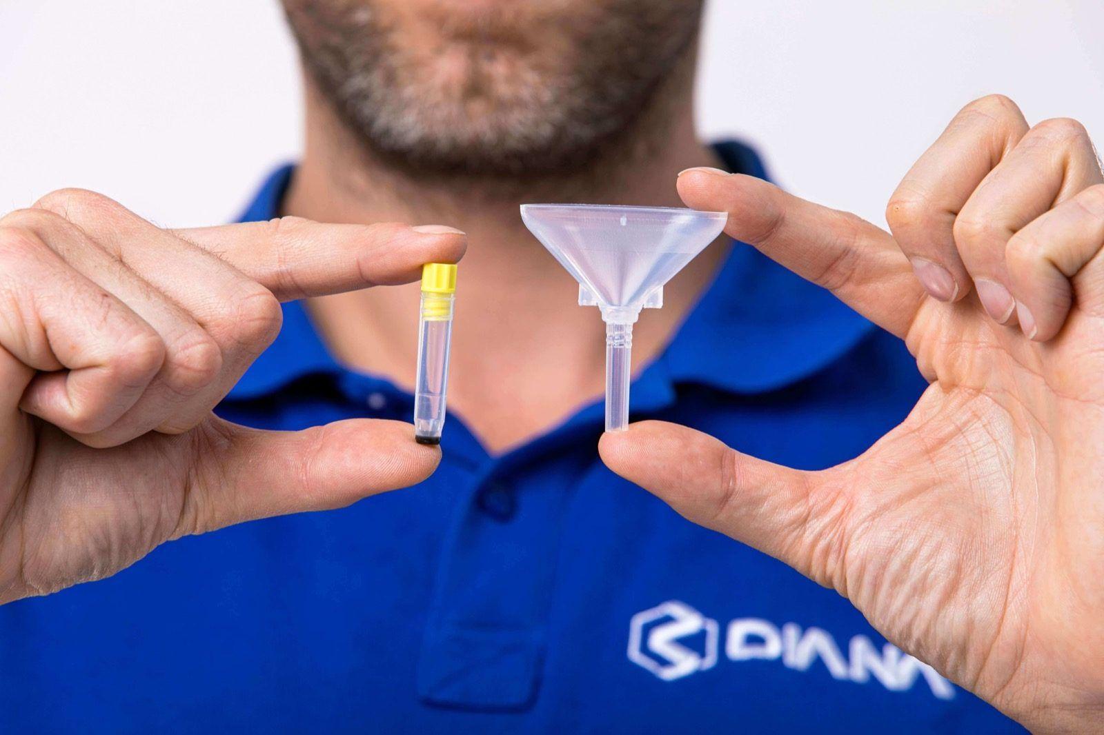 Scientist in a DIANA shirt holding a sample tube and a funnel